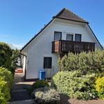 Haus mit Balkon, gepflegtem Garten und blauem Mülleimer.