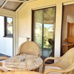 Terrasse mit Rattanstühlen und Marmor-Tisch. Durchgehendes Glas zur Wohnung.