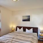 Schlafzimmer mit Bett, zwei Nachttischen und einem Wandbild.