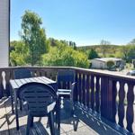 Terrasse mit Tisch und Stühlen, Blick auf grüne Bäume und Wohnhäuser.