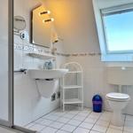 Badezimmer mit Toilette, Waschbecken und Dusche. Fenster mit Blick nach draußen.