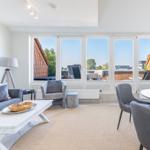 Wohn- und Essbereich mit großem Fensterblick auf Balkon und Dächer.