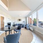 Essbereich mit Tisch und Stühlen. Wohnbereich mit Sofa und Blick auf Balkon.