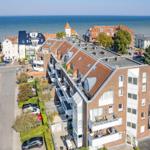 Meerblick auf Wohnhäuser mit Balkonen und gepflegten Gärten