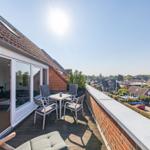 Terrasse mit Sitzgruppe und Blick auf Wohngebiet unter blauem Himmel