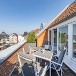 Terrasse mit Tisch und Stühlen, Blick auf Wohnhäuser und Dächer.