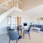 Wohnbereich mit Essbereich, Sofa und Treppe zur oberen Etage.