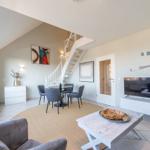 Wohn- und Essbereich mit Treppe und TV. Rundteppich, Sofa und Esstisch.