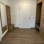 Eingangsbereich mit Spiegel, Kleiderschrank und Tür.