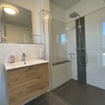 Badezimmer mit Dusche, Waschbecken und Spiegel