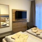Zimmer mit Bett, Fernseher und Spiegel. Vorhang vor Fenster.