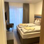 Schlafzimmer mit Doppelbett, TV und Fenster mit Vorhängen.