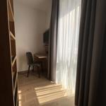 Schreibtisch mit Stuhl und TV unter Fenster mit Vorhängen.