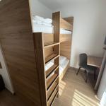 Zimmer mit Doppelstockbett, Schreibtisch und Stuhl.