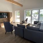 Wohnzimmer mit Sofa, Sessel und Fernseher an der Wand.