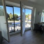 Offener Raum mit Essbereich und Terrasse. Große Fenster und Türen zur Außenterrasse.