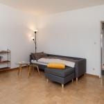 Zimmer mit Sofa-Bett, Bücherregal und angrenzender Badewanne.