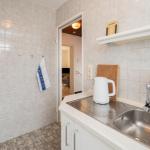 Küche mit Spüle, Wasserkocher und Küchenbrett. Hintergrund: Wohnbereich.