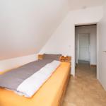 Schlafzimmer mit Dachschräge, Bett und Kleiderständer