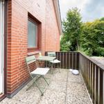 Terrasse mit Tisch, zwei Stühlen und Blick auf grüne Bäume.