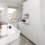 Küche mit weißen Schränken, Herd und Fensterblick.