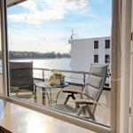 Balkon mit Sitzgelegenheiten und Blick auf Wasser und Gebäude.