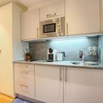 Küche mit weißen Schränken, Edelstahlspüle und Mikrowelle.