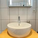 Waschbecken mit Spiegel und Holzuntersetzer