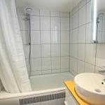 Badezimmer mit Dusche, Waschbecken und Spiegel.