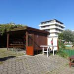 Terrasse mit Holzüberdachung, Tisch, Bänke und Bootsständer vor Wohnhaus