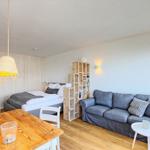 Ein Raum mit Sofa, Bett, Esstisch und Holzwand.