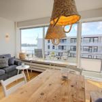 Wohnung mit Essbereich, Sofa und Balkon mit Meerblick.