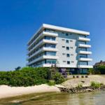 Moderne Wohnanlage am Strand mit Balkonen und großzügigen Fenstern.