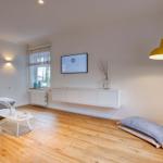 Wohnzimmer mit Sofa, Fernseher und gelber Stehlampe.