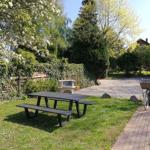 Garten mit Picknicktisch, Grill und Fahrrad auf Kiesweg.