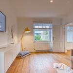 Wohnzimmer mit Fernseher, Sofa, Holzboden und Fenster.
