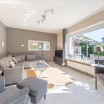 Wohnzimmer mit Sofa, Sessel und großem Fenster zur Terrasse.