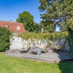 Hinterhof mit Holzterrasse, Liegen, Hängematte und Buddha-Statue.