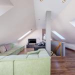 Wohnzimmer mit grünem Sofa, Holzboden und Dachschrägen mit Dachfenstern.