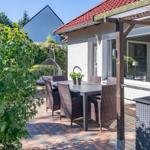 Terrasse mit Tisch, Stühlen und Pavillon. Hinterhof mit Hängesessel und Pflanzen.