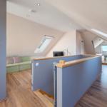 Dachgeschosswohnung mit Sofa, Bett und Dachfenstern.