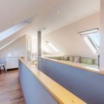 Dachgeschoss mit Sitzbank, Schreibtisch und Dachfenstern.