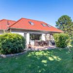 Haus mit rotem Dach, Terrasse und Garten mit Obstbaum.