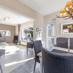 Essbereich mit Tisch und Stühlen, dahinter Wohnzimmer mit Sofa und TV.