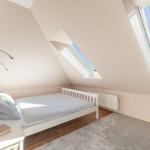 Schlafzimmer mit Dachschrägen, Bett, Fenster und Teppichboden.