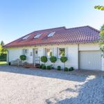 Einfamilienhaus mit Garage, Terrasse und gepflegtem Garten. Dach mit Dachfenstern.