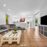 Wohnzimmer mit Sofa aus Paletten, Glas-Tisch und Fernseher.