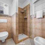 Badezimmer mit Dusche, Badewanne und Toilette. Wandfliesen und Mosaikboden.