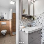 Bad mit Waschbecken, Spiegelschrank und Dusche. Fliesenwand und Toilette sind sichtbar.