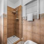 Bad mit Dusche, Bidet und Heizkörper. Fliesen in Terrakottaton.